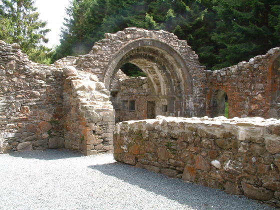 The inside of a ruined church with a large arch still remaining